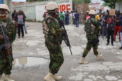 Kenyan police patrol an area near the international airport as a man holds a sign with a welcome message and a plea for jobs, in Port-au-Prince, Haiti, on July 3, 2024.