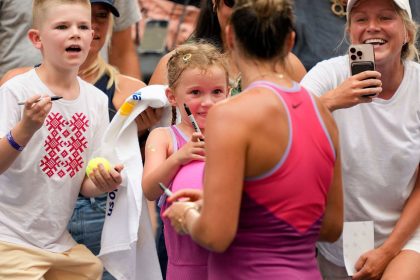 Aryna Sabalenka signs autographs for fans, including for a young fan dressed up like her, after defeating Lucia Bronzetti in the second round of the US Open.