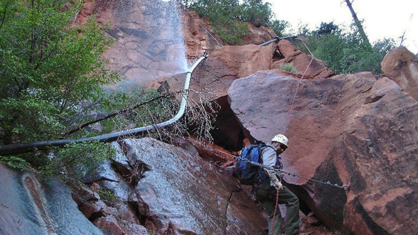 Water sprays from a break in an exposed section of the Transcanyon Waterline as a worker attempts repairs in this undated photo provided by the National Park Service.