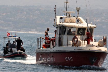 Divers enter Porticello harbor near Palermo, with the body of Hannah Lynch at the back of the boat on Friday.