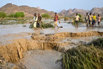 Sudanese people cross a damaged road after the collapse of the Arba'at Dam following heavy rains and torrential floods on August 25, 2024.