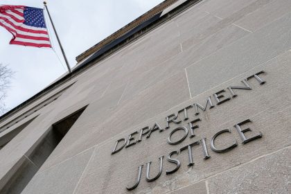 The US Flag flies above a sign marking the US Department of Justice headquarters building on January 20, 2024, in Washington, DC.