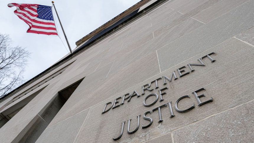 The US Flag flies above a sign marking the US Department of Justice headquarters building on January 20, 2024, in Washington, DC.