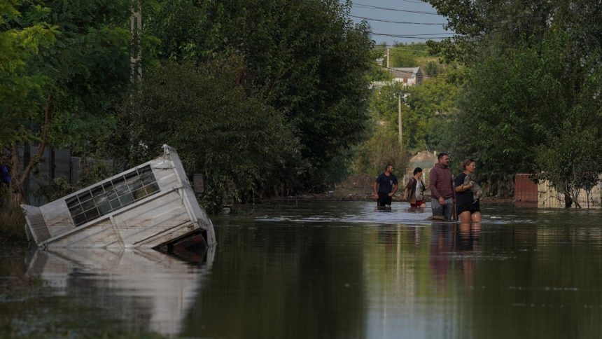 People walk on a flooded road after heavy rain triggered flooding in Cuza Voda, Galati county, Romania, September 15, 2024.