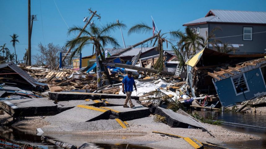 TOPSHOT - A man walks over a broken section of the Pine Island Road in the aftermath of Hurricane Ian in Matlacha, Florida on October 1, 2022. - Shocked Florida communities counted their dead October 1, 2022, as the full scale of the devastation came into focus, two days after Hurricane Ian tore into the coastline as one of the most powerful storms ever to hit the United States.