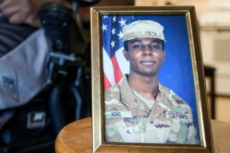 FILE - A portrait of American soldier Travis King is displayed as his grandfather, Carl Gates, talks about his grandson on July 19, 2023, in Kenosha, Wis. The Biden administration is extending for another year a ban on the use of U.S. passports for travel to North Korea, the State Department said Tuesday. The latest extension comes as tensions with North Korea are rising over its nuclear and ballistic missile programs and the uncertain status of Travis King, a U.S. service member who last month entered the country through its heavily armed border. (AP Photo/Morry Gash, File)