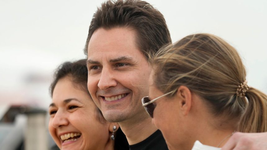 Michael Kovrig embraces his separated wife Vina Nadjibulla and sister Ariana Botha after arriving at Pearson International Airport in Toronto, on September 25, 2021.