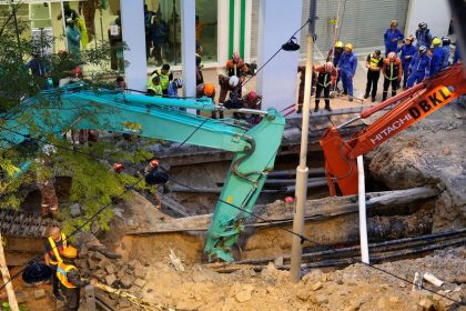 Fire and Rescue department workers search for a woman who fell into a sinkhole in Kuala Lumpur on Aug. 23, 2024.