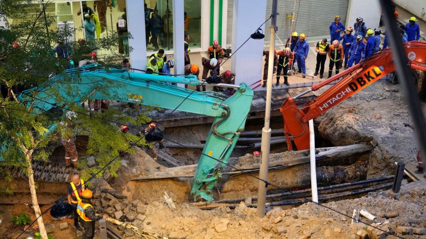 Fire and Rescue department workers search for a woman who fell into a sinkhole in Kuala Lumpur on Aug. 23, 2024.