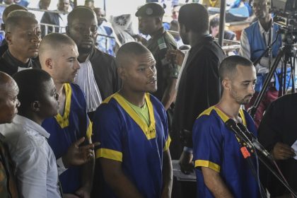 From left: Tyler Thompson Jr, Marcel Malanga and Benjamin Reuben Zalman-Polun, all American citizens, face the court in Kinshasa with 52 other defendants on June 7, 2024.