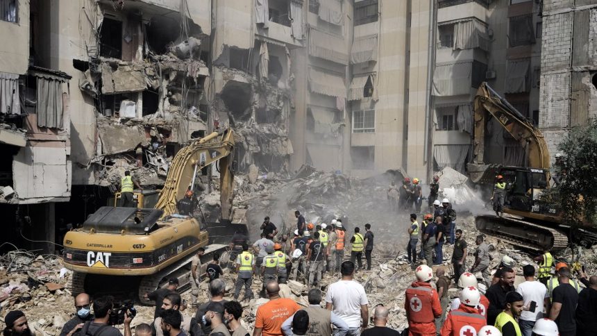 Emergency workers use excavators to clear the rubble at the site of Friday's Israeli strike in Beirut's southern suburbs, Saturday, Sept. 21, 2024.