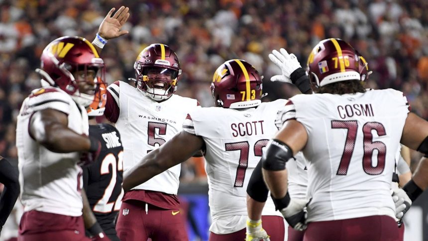 Jayden Daniels (5) celebrates throwing a touchdown pass to offensive tackle Trent Scott (73) against the Cincinnati Bengals.