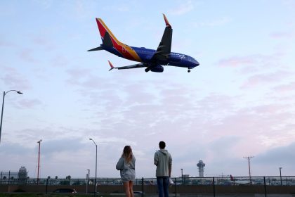 People view a Southwest Airlines plane landing from a park next to Los Angeles International Airport.