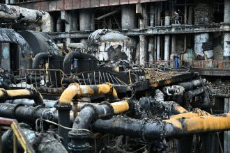 Workers remove debris in a turbine hall full of scorched equipment at a power plant in Ukraine in April 2024.