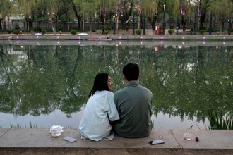 A couple sit together as they fish along a canal on April 12, 2024 in Beijing, China.