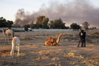 Residents stand near camels as they watch smoke billowing during the demolition by Israeli security forces of the unrecognized bedouin community of Wadi al Khalil, in the southern Negev desert, near the town of Hura on May 8.