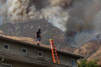 A man waters the roof of his home as the Line Fire burns in the foothills of the San Bernardino Mountains, forcing evacuations.