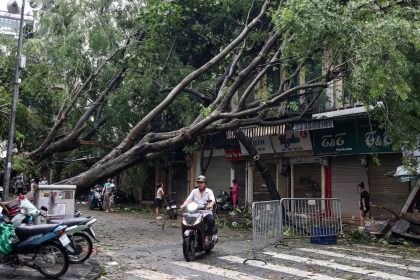 A man rides his motorbike past fallen trees on a street after Super Typhoon Yagi hit Hanoi, Vietnam, on Sunday.