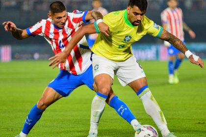 Brazil's Lucas Paquetá tries to shield the ball from Paraguay's Juan Cáceres.