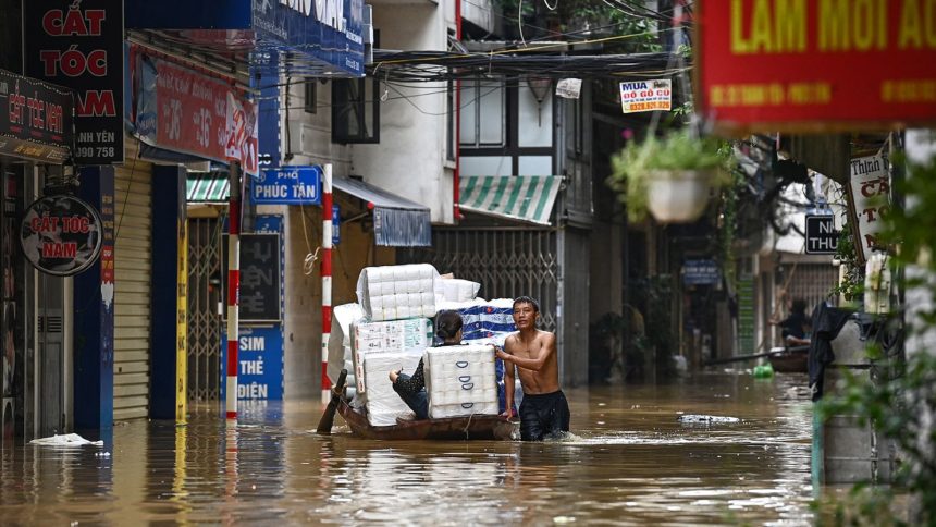 People transport basic commodities on a boat through flood waters on a street in Hanoi on September 12, 2024, as heavy rains in the aftermath of Typhoon Yagi brought flooding to northern Vietnam.