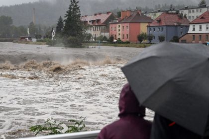 People shelter from the rain under umbrellas as they walk across a bridge over the Biala River in Glucholazy, southern Poland on Saturday.