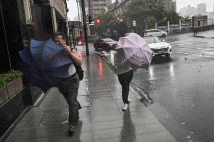 Pedestrians struggle with their umbrellas in strong winds and rain from the passage of Typhoon Bebinca in Shanghai on September 16, 2024.