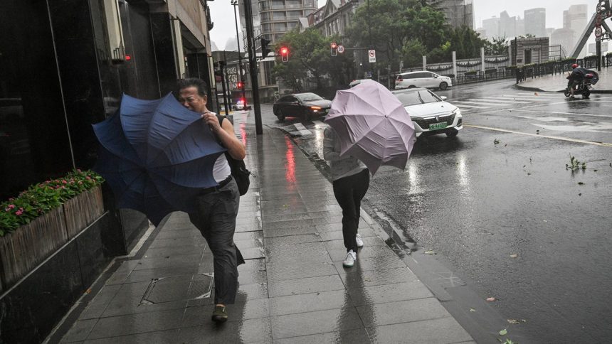 Pedestrians struggle with their umbrellas in strong winds and rain from the passage of Typhoon Bebinca in Shanghai on September 16, 2024.