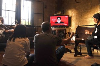 People watch a televised speech by the leader of the Hezbollah movement Hassan Nasrallah inside a house in the southern Lebanese village of Zawatar on September 19.