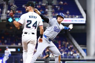 Shohei Ohtani of the Los Angeles Dodgers reacts after stealing third base ahead of Connor Norby #24 of the Miami Marlins to register his 50th stolen base of the season.