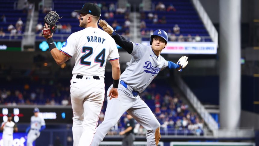 Shohei Ohtani of the Los Angeles Dodgers reacts after stealing third base ahead of Connor Norby #24 of the Miami Marlins to register his 50th stolen base of the season.