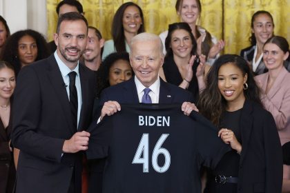 President Joe Biden is presented a jersey from NJ/NY Gotham FC head coach Juan Carlos Amorós and forward Midge Purce during a ceremony.