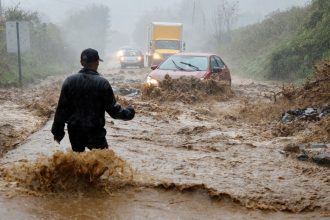 A person wades through fast-flowing floodwater on the outskirts of Boone, North Carolina, to assist a stranded driver as Helene strikes on September 27, 2024.