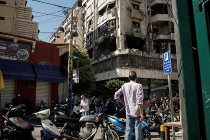 People look at a damaged building at the site of an Israeli strike on central Beirut's Bachoura neighborhood on October 3.