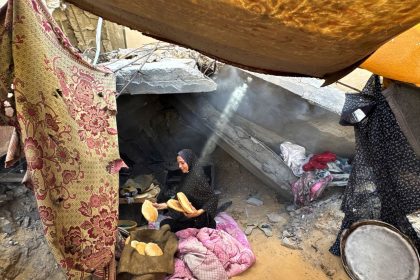 A Palestinian woman holds pita bread in a makeshift tent in Khan Younis, southern Gaza, on October 7, 2024.