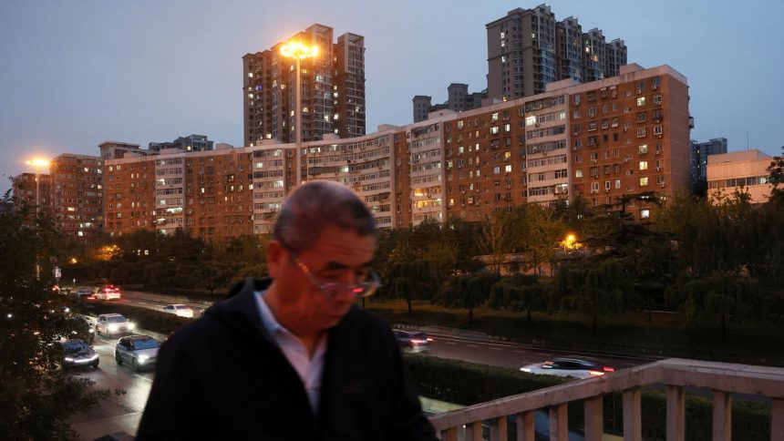 A man walks on a pedestrian bridge past residential buildings in Beijing, China, on October 16, 2024.