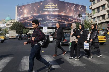 Iranians walk next to an anti-Israel billboard on a street after several explosions were heard, in Tehran, Iran, on Saturday.