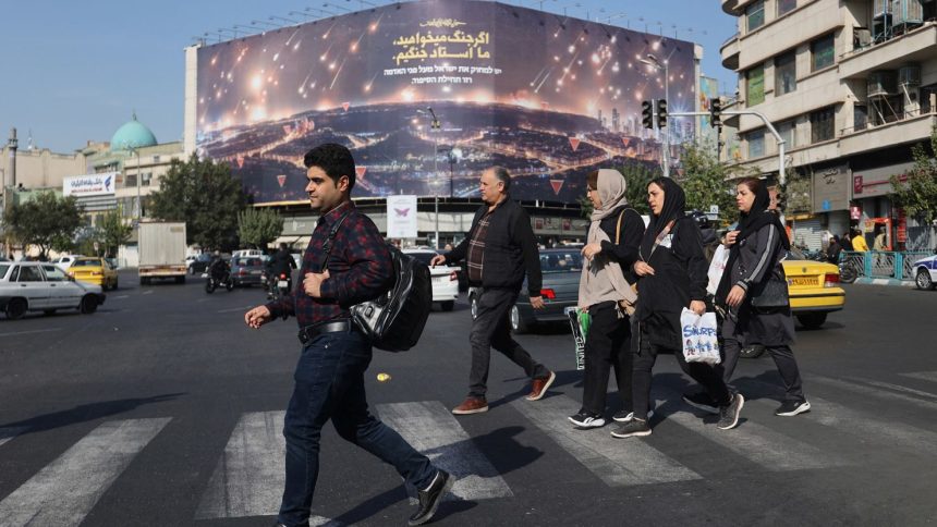 Iranians walk next to an anti-Israel billboard on a street after several explosions were heard, in Tehran, Iran, on Saturday.