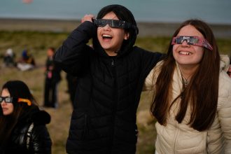 People watch as an annular solar eclipse appears Wednesday in the sky over Puerto San Julián, Argentina.