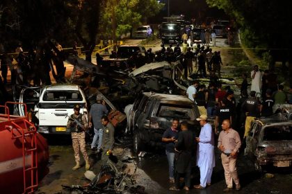 Security officials examine the site of an explosion that caused injures and destroyed vehicles outside Karachi airport, Pakistan, early Monday, Oct. 7.