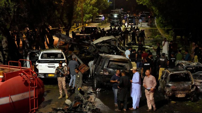 Security officials examine the site of an explosion that caused injures and destroyed vehicles outside Karachi airport, Pakistan, early Monday, Oct. 7.