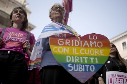 A woman shows a banner reading "we shout it from the heart, now rights" during a pro-surrogacy press conference in Rome, Tuesday, October 15, 2024.