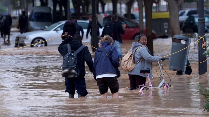 People walk through flooded streets in Valencia, Wednesday, October 30, 2024.