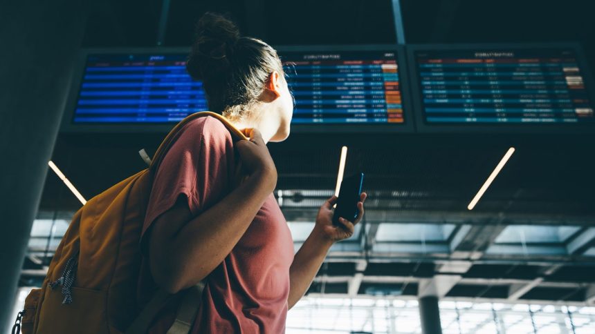 A woman checks the departures schedule at an airport.