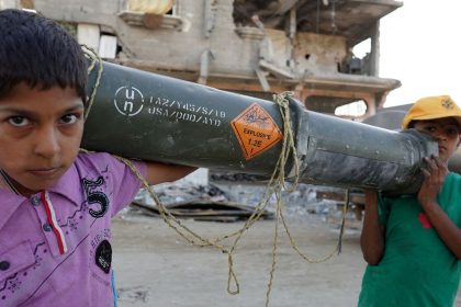 Palestinian children carry an empty US ammunition container in Khan Younis in the southern Gaza Strip on May 16, 2024.