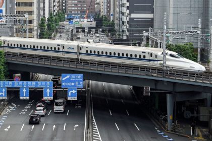 A "shinkansen", or high-speed bullet train, passes along the tracks above traffic on the streets below, near Shimbashi station in central Tokyo on May 22, 2024.