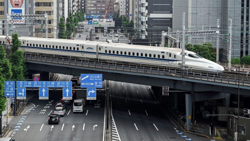 A "shinkansen", or high-speed bullet train, passes along the tracks above traffic on the streets below, near Shimbashi station in central Tokyo on May 22, 2024.