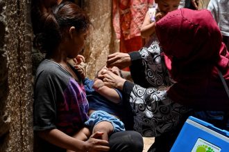 A health worker administers polio vaccine drops to a child during a vaccination campaign in Karachi on June 3, 2024.