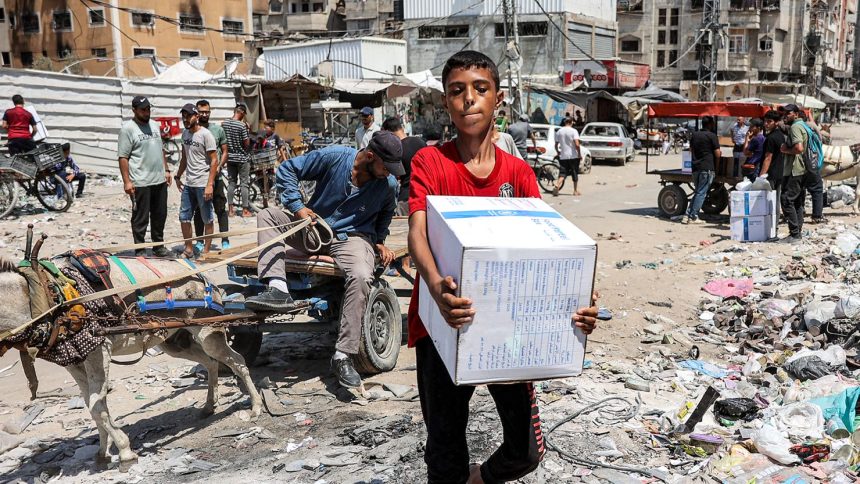 A boy carries a humanitarian aid package provided by the United Nations Relief and Works Agency for Palestine Refugees (UNRWA) in central Gaza City on August 27.