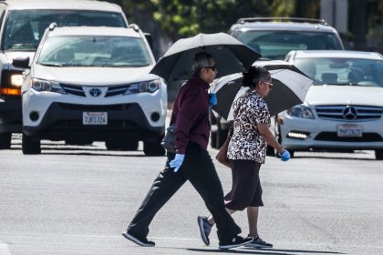 People cross the road amid hot weather in Covina, California, on Wednesday.