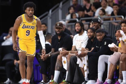 LeBron James watches the game from the bench as Bronny James makes his preseason debut.